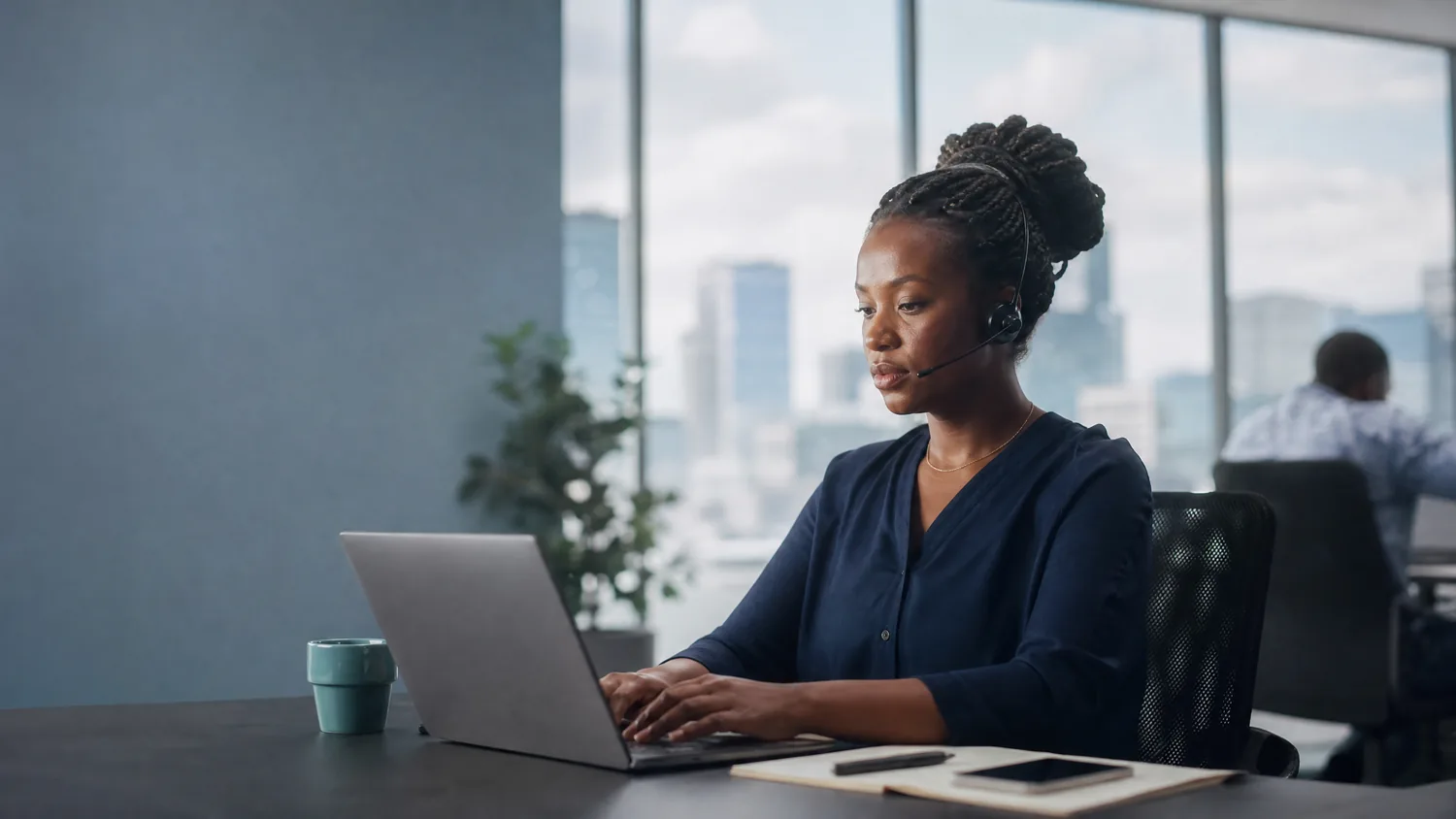 An agent in Nairobi taking a call on a headset at her laptop